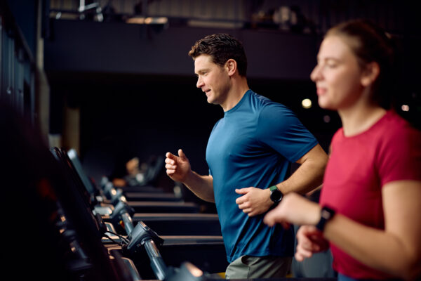 Mid adult sportswoman running on treadmill at health club.
