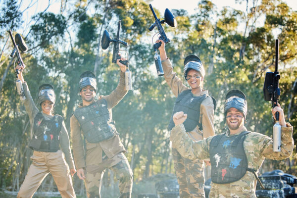 Team, paintball and portrait in celebration for winning, victory or achievement on the battlefield .